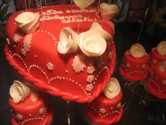 Свадебный торт в виде сердца в розах с капкейками